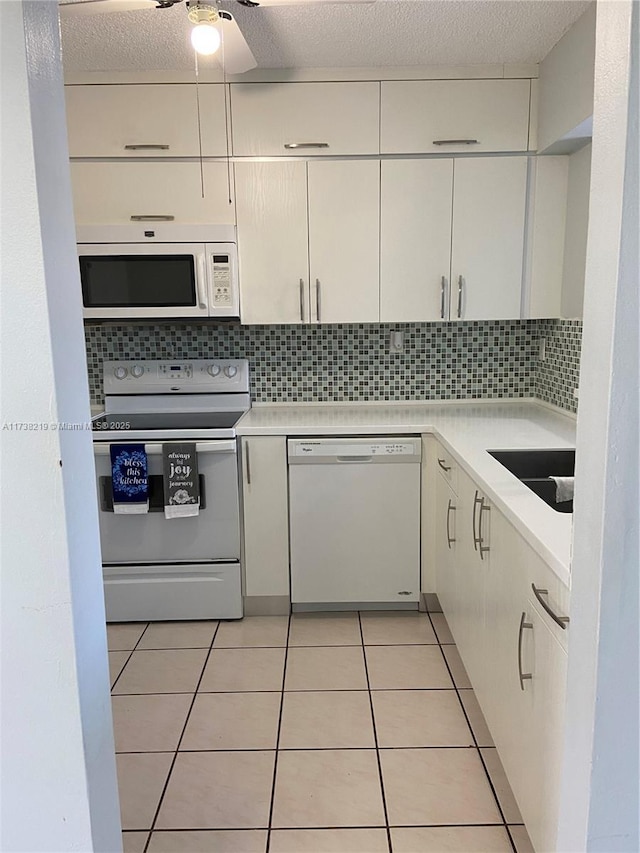 kitchen with sink, decorative backsplash, light tile patterned floors, white appliances, and a textured ceiling