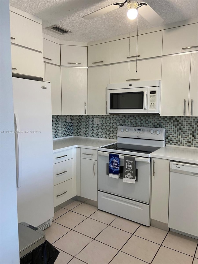 kitchen with white appliances, ceiling fan, white cabinetry, backsplash, and light tile patterned flooring