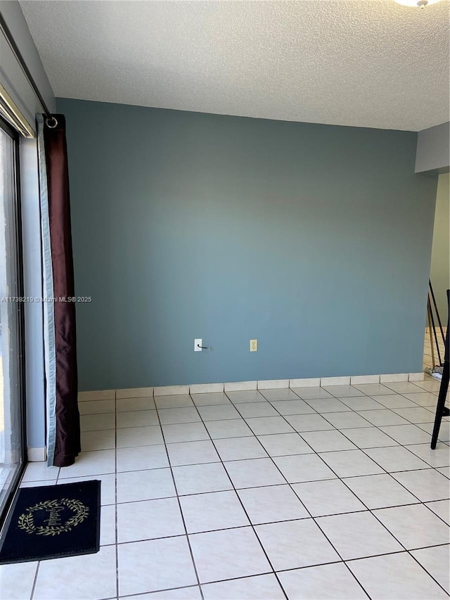 tiled empty room with a textured ceiling