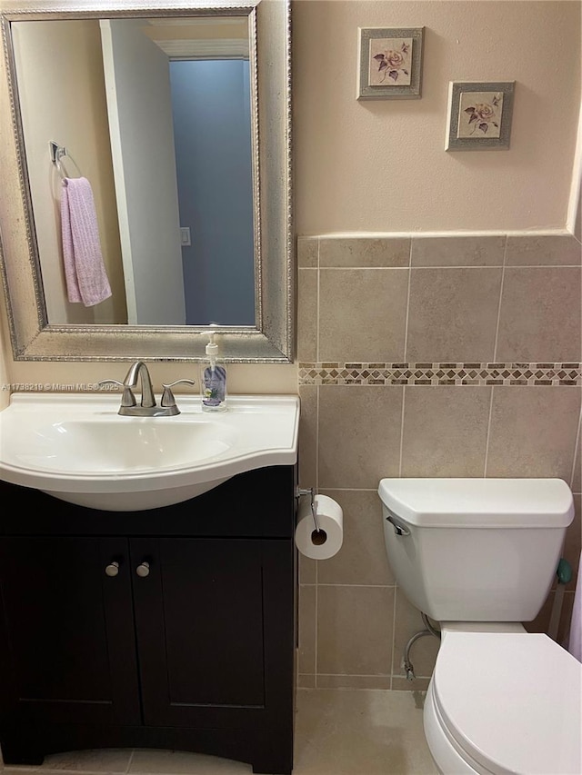 bathroom with vanity, tile walls, and toilet