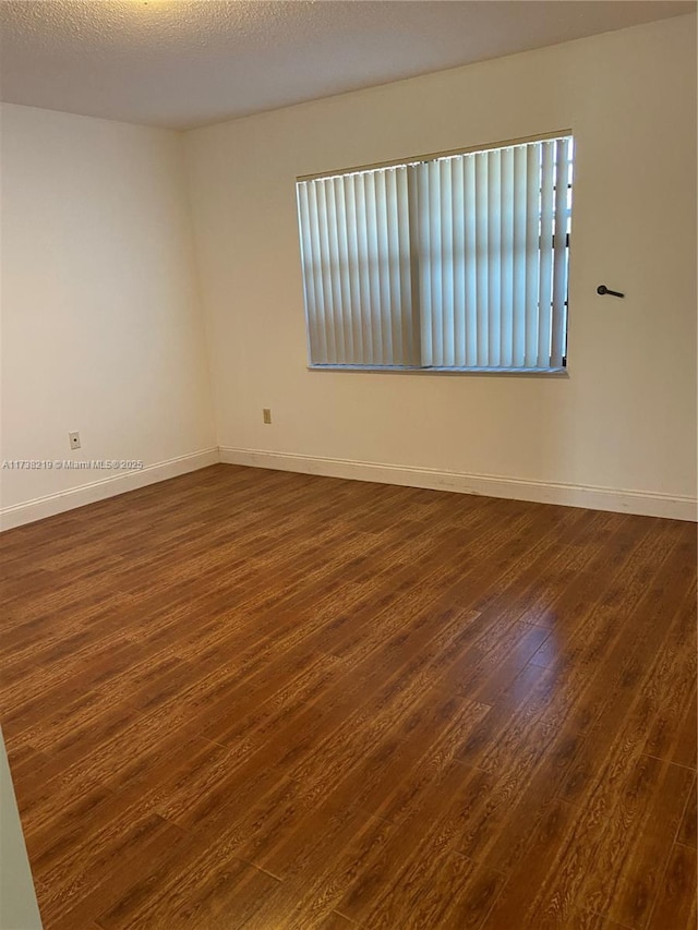 spare room with dark hardwood / wood-style floors and a textured ceiling