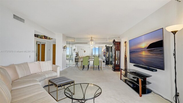 carpeted living room featuring a notable chandelier