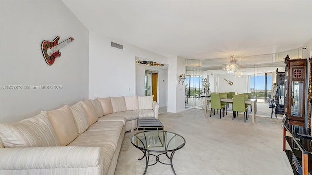 carpeted living room with an inviting chandelier