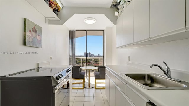 kitchen featuring stainless steel appliances, sink, light tile patterned floors, and white cabinets