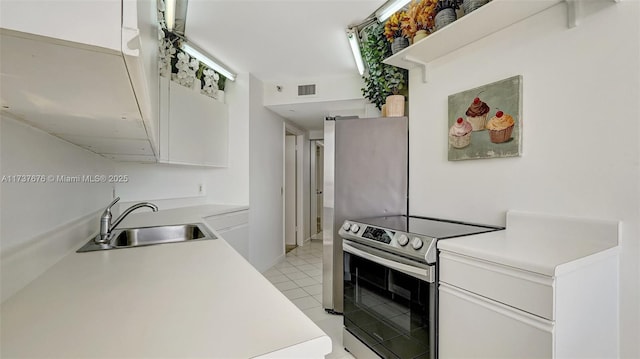 kitchen featuring electric stove, sink, white cabinets, and light tile patterned flooring