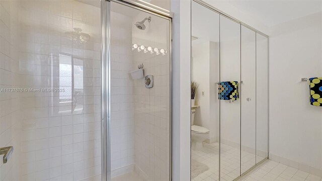 bathroom with an enclosed shower, tile patterned floors, and toilet