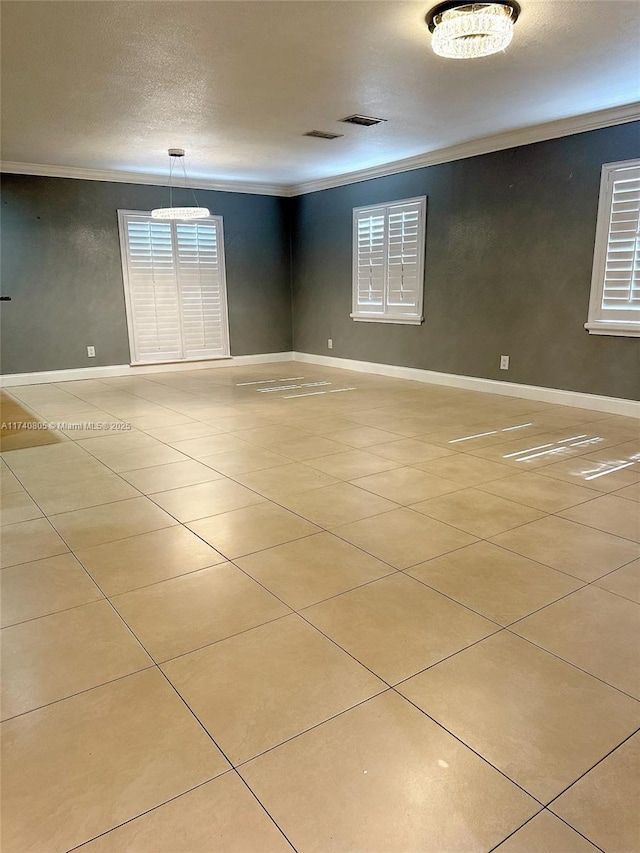 tiled empty room featuring crown molding and a textured ceiling