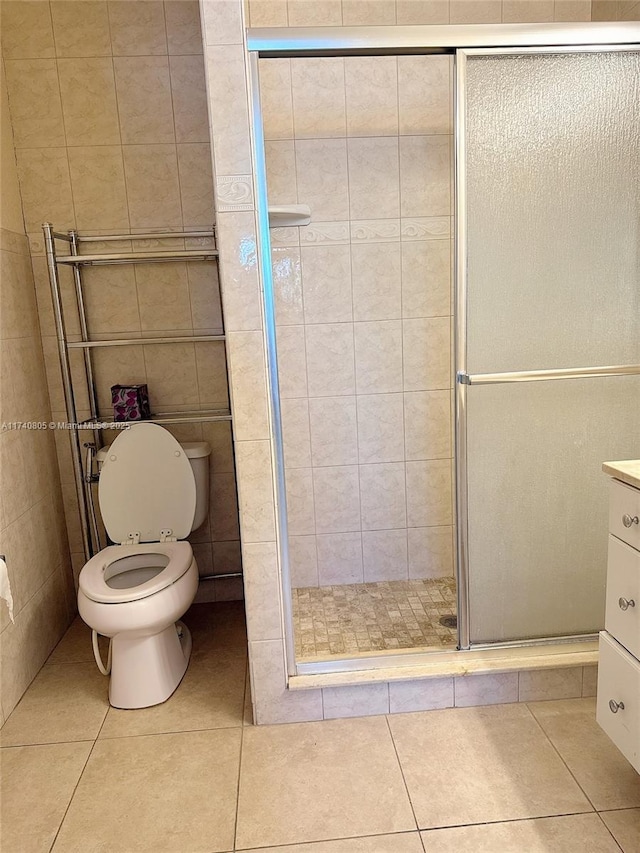 bathroom featuring tile patterned flooring, vanity, tile walls, and walk in shower