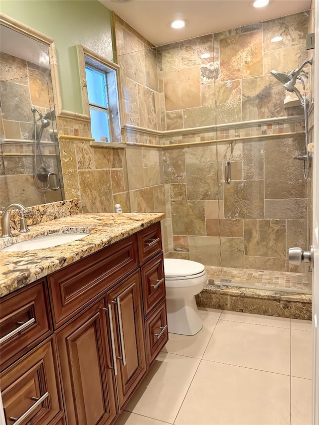 bathroom with walk in shower, tile patterned floors, toilet, tile walls, and vanity