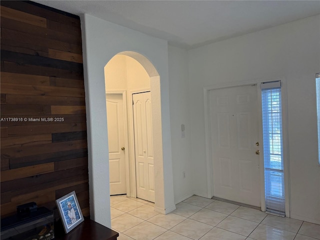 foyer with light tile patterned floors and wooden walls