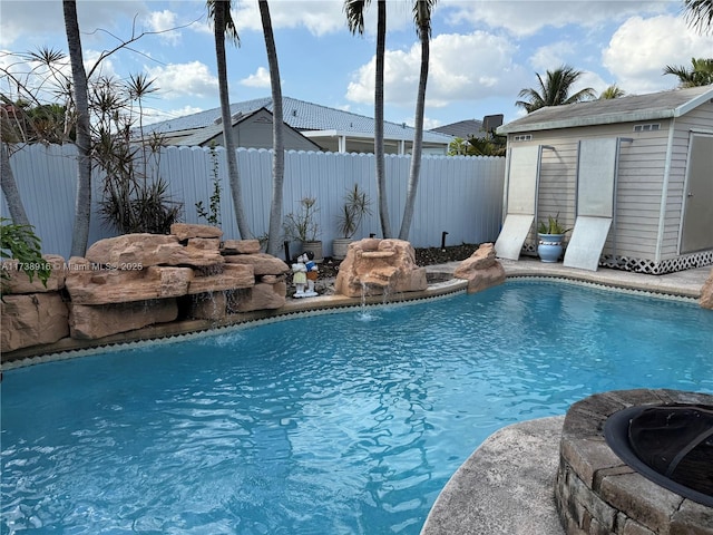 view of pool with a storage shed, a fire pit, and pool water feature