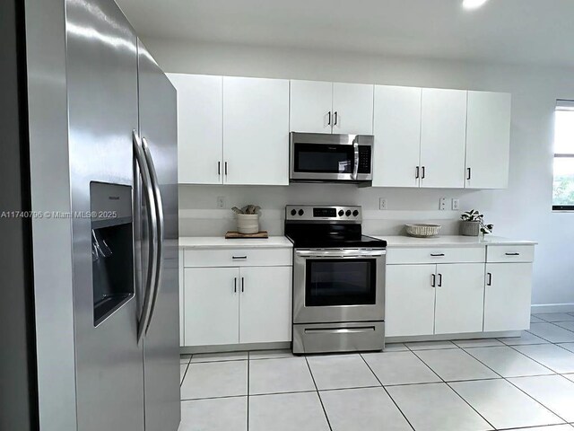 kitchen with stainless steel appliances, white cabinetry, and light tile patterned floors