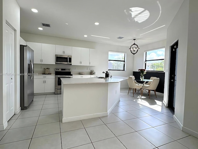 kitchen featuring white cabinetry, stainless steel appliances, light tile patterned floors, and pendant lighting