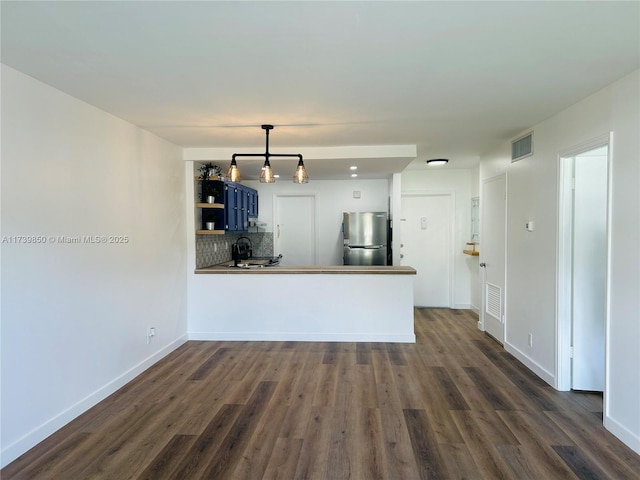 kitchen featuring blue cabinets, tasteful backsplash, stainless steel refrigerator, dark hardwood / wood-style flooring, and kitchen peninsula