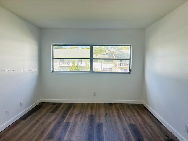 spare room with a healthy amount of sunlight and dark wood-type flooring