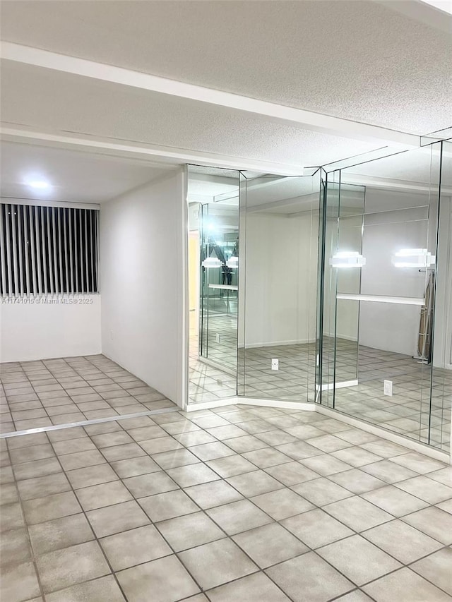 empty room with a textured ceiling and light tile patterned floors