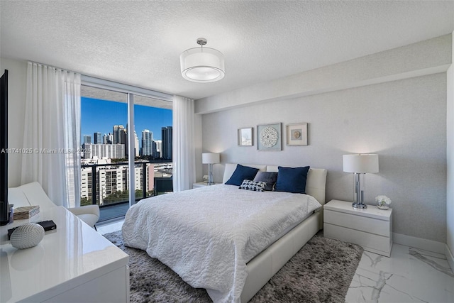 bedroom featuring a textured ceiling, access to exterior, and a wall of windows