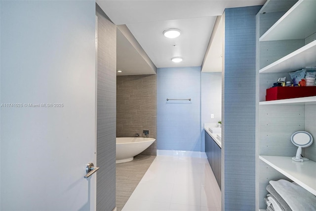 bathroom featuring vanity, a bath, tile patterned flooring, and tile walls