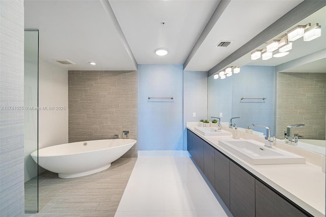 bathroom featuring tile walls, vanity, tile patterned floors, and a tub to relax in