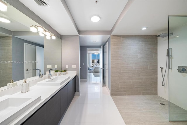 bathroom with vanity, tile walls, tile patterned floors, and a tile shower