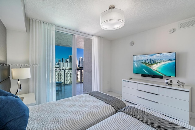 bedroom with access to exterior, expansive windows, and a textured ceiling