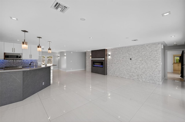 2816 NE 24th Pl, Fort Lauderdale, FL 33305 - kitchen featuring stainless steel microwave, light tile patterned floors, white cabinets, hanging light fixtures, and modern cabinets