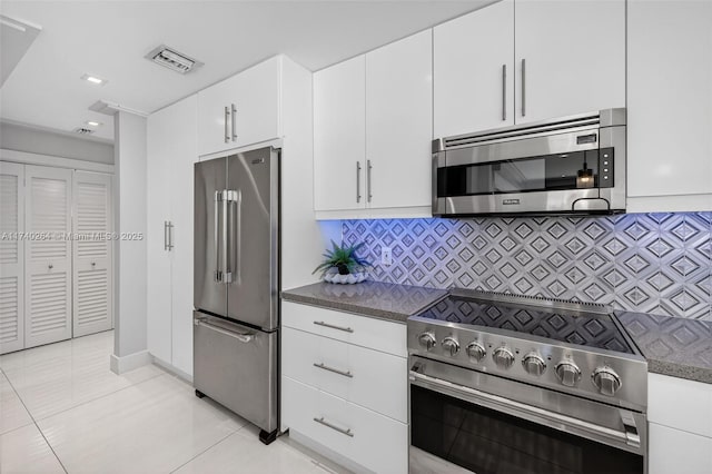 2816 NE 24th Pl, Fort Lauderdale, FL 33305 - kitchen with appliances with stainless steel finishes, white cabinetry, decorative backsplash, light tile patterned floors, and dark countertops