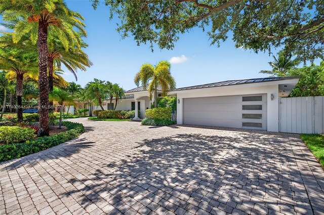 2816 NE 24th Pl, Fort Lauderdale, FL 33305 - view of front of house featuring stucco siding, decorative driveway, a standing seam roof, an attached garage, and a metal roof