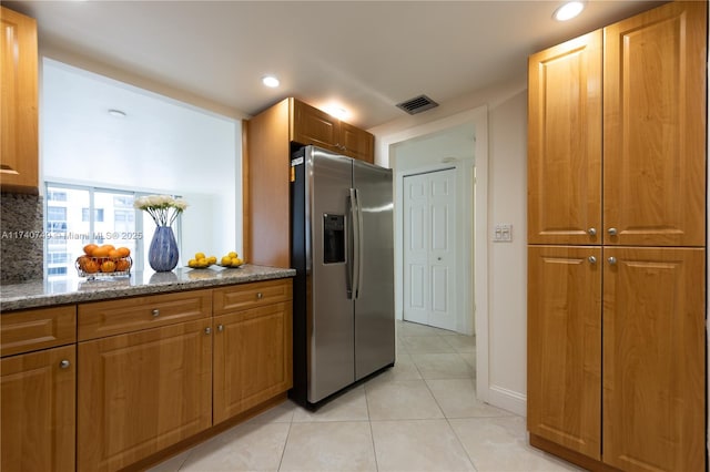 kitchen with light tile patterned flooring, stone countertops, decorative backsplash, and stainless steel fridge with ice dispenser