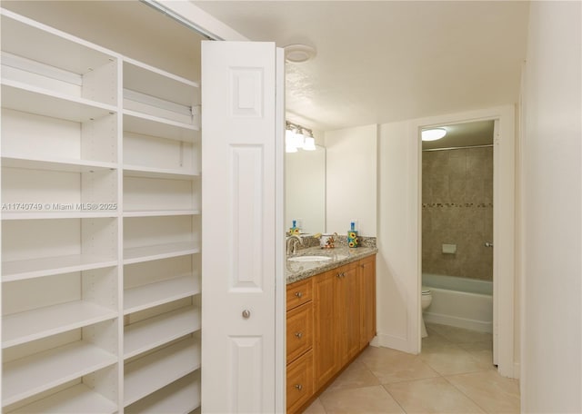 full bathroom with tiled shower / bath, vanity, toilet, and tile patterned flooring