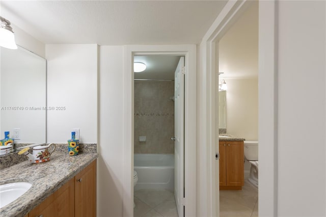 full bathroom with vanity, tiled shower / bath, tile patterned floors, and toilet