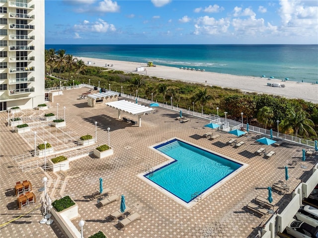 view of swimming pool with a water view and a beach view