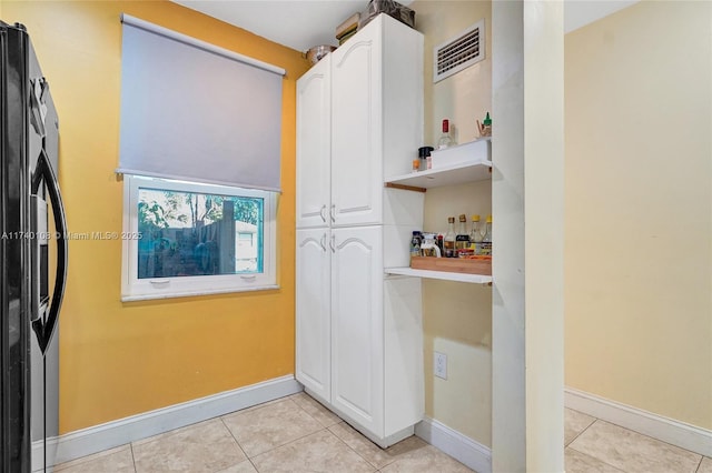 kitchen featuring white cabinetry, light tile patterned floors, and black fridge with ice dispenser