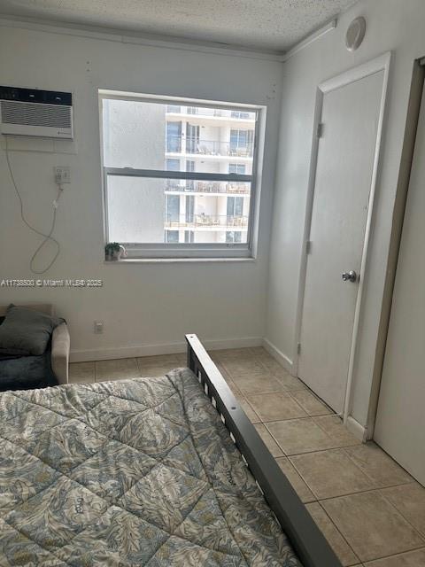 unfurnished bedroom featuring a wall mounted AC, a textured ceiling, and light tile patterned floors