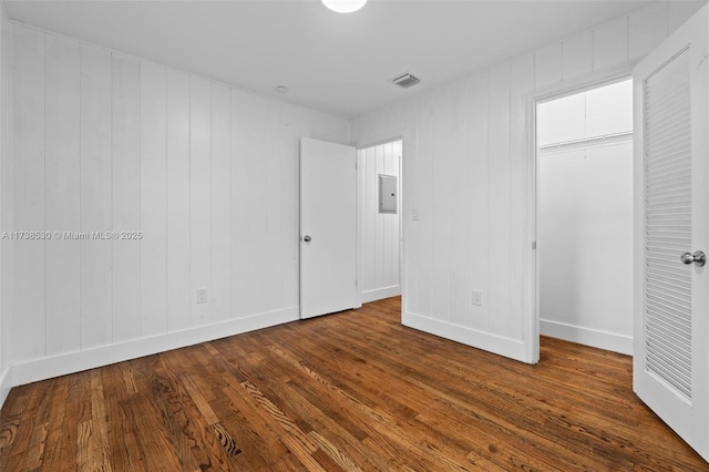 unfurnished bedroom featuring dark wood-type flooring, electric panel, and a closet