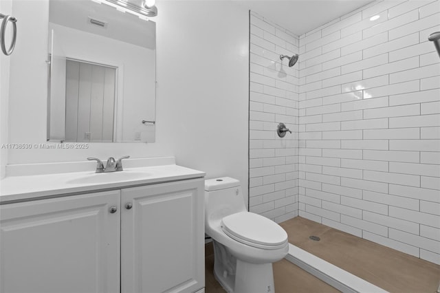 bathroom with vanity, a tile shower, and toilet