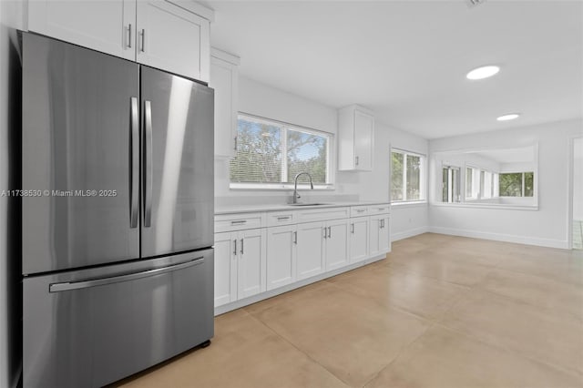 kitchen featuring stainless steel fridge, sink, and white cabinets