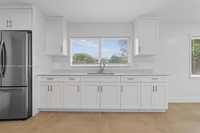 kitchen featuring white cabinetry, sink, and stainless steel refrigerator