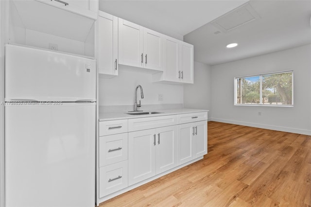 kitchen with white cabinetry, sink, light hardwood / wood-style floors, and white refrigerator