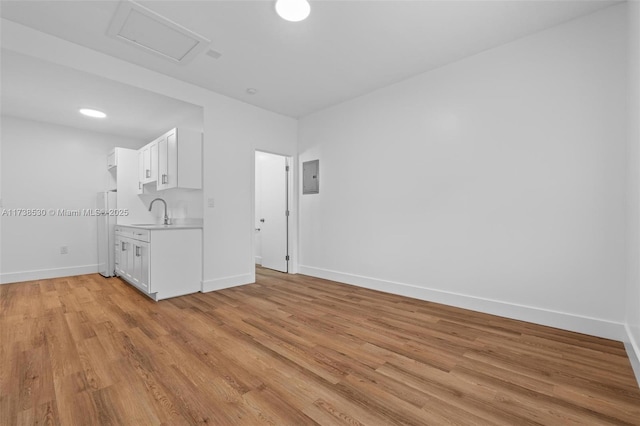 spare room featuring sink, electric panel, and light wood-type flooring