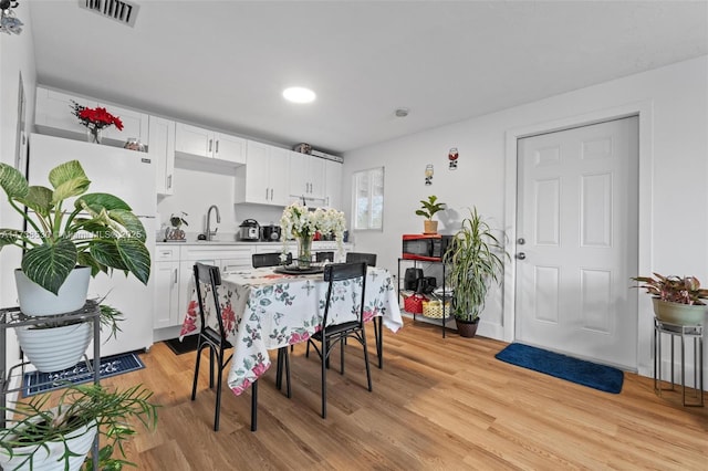 dining area with sink and light wood-type flooring