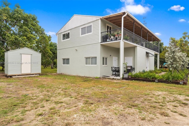 rear view of property featuring a balcony, a storage unit, a patio, and a lawn