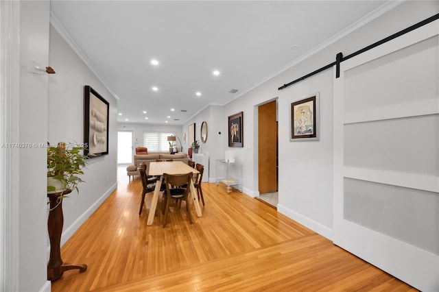 dining area with hardwood / wood-style flooring, ornamental molding, and a barn door