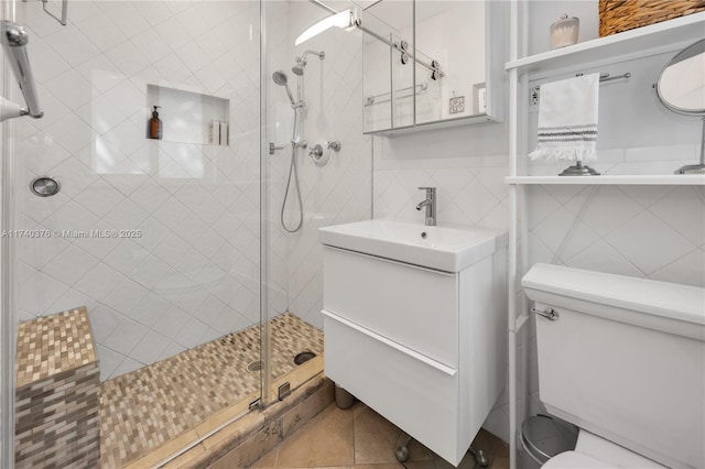 bathroom featuring walk in shower, vanity, toilet, and tile walls