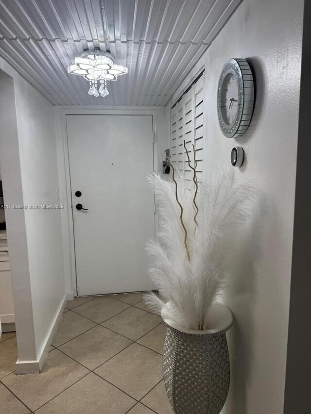 doorway to outside featuring light tile patterned flooring and a chandelier