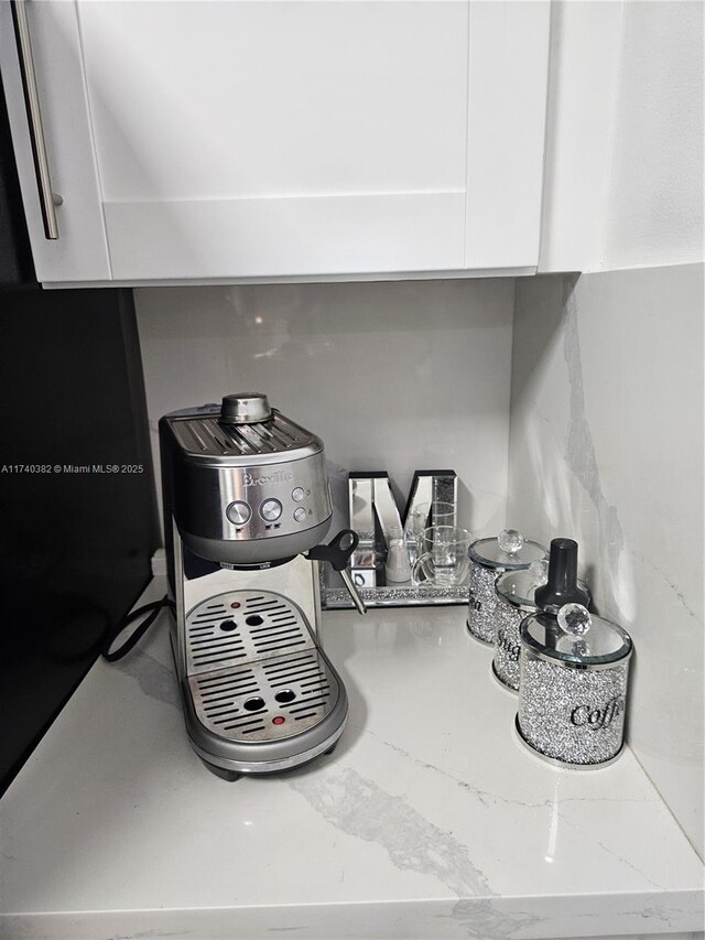 room details featuring white cabinets and light stone counters