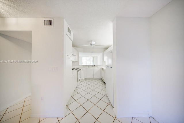 hallway featuring sink, light tile patterned floors, and a textured ceiling
