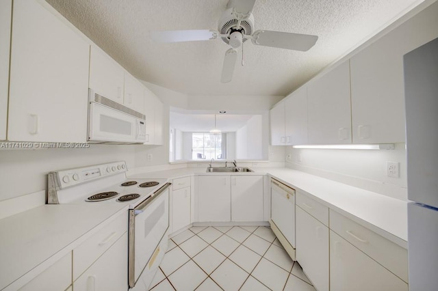 kitchen featuring sink, white cabinets, white appliances, light tile patterned floors, and a textured ceiling