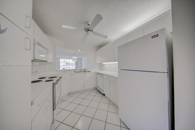 kitchen featuring sink, white cabinets, light tile patterned floors, white appliances, and a textured ceiling