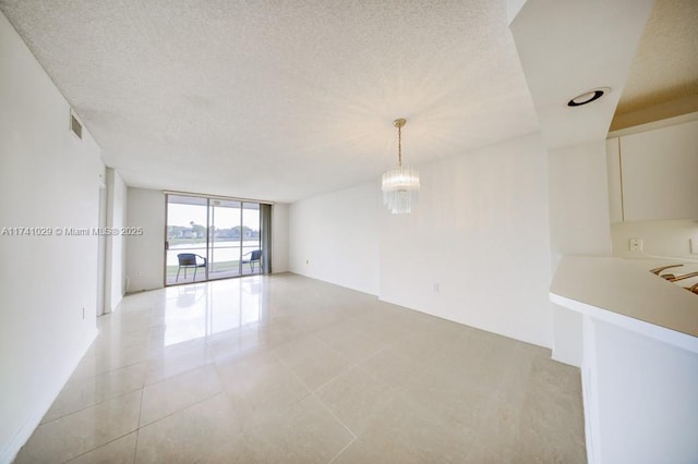 spare room with an inviting chandelier, light tile patterned floors, floor to ceiling windows, and a textured ceiling